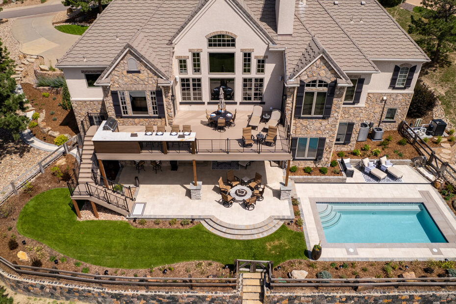 aerial view of an outdoor living space with a pool, second-level deck, outdoor kitchen, paver patio and firepit