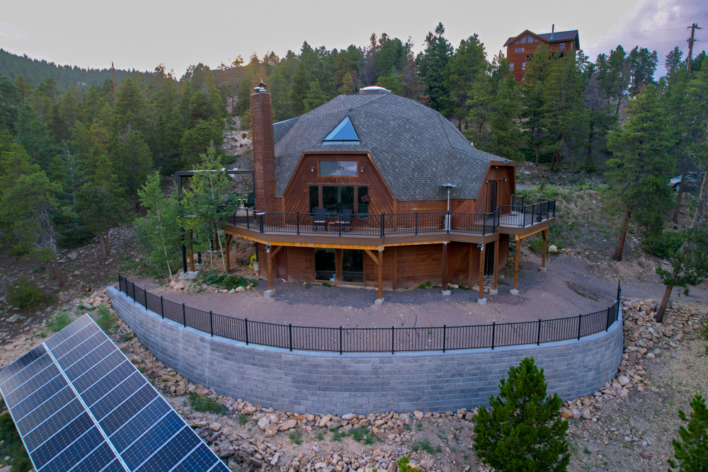 A home in the mountains with a retaining wall and wrap around deck