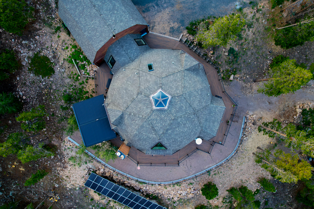 An ariel view of home in the mountains with a retaining wall and wrap around deck