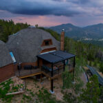 A house in the mountains with large deck and retaining wall.