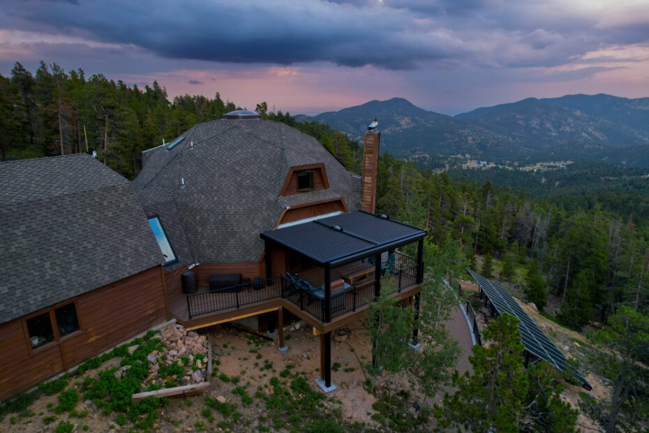 A house in the mountains with large deck and retaining wall.