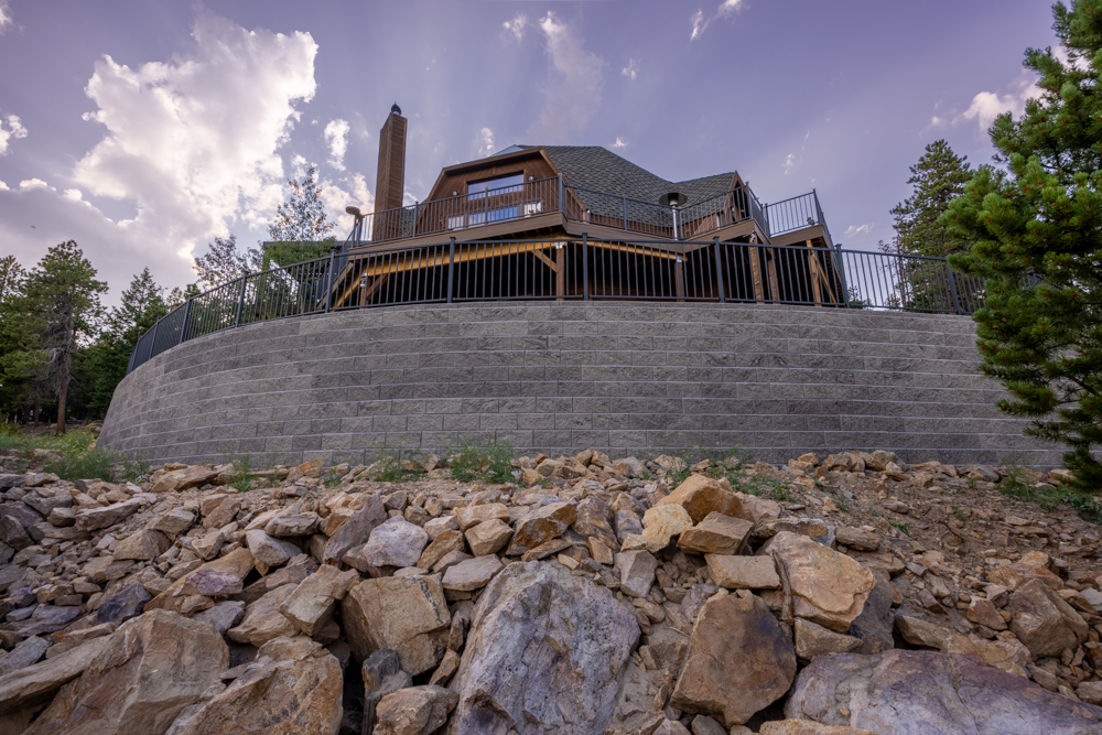 A home in the mountians with a large retaining wall supported with rock