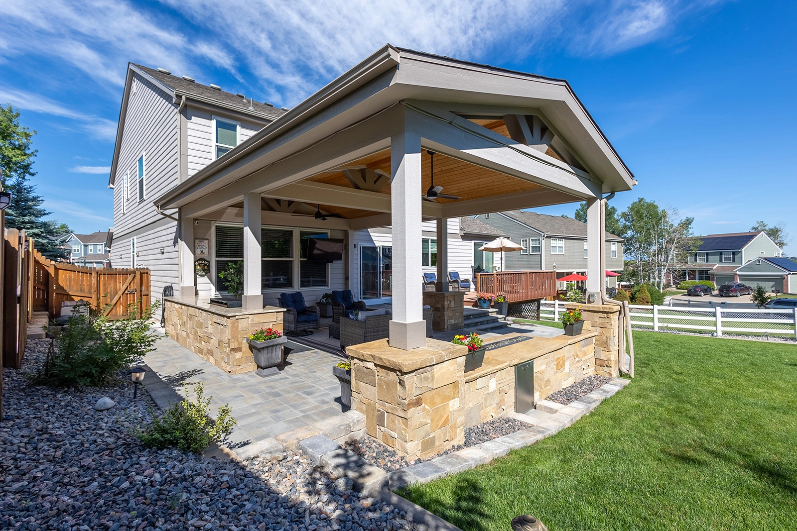 Gable-roofed covered patio with a stone outdoor kitchen and seating